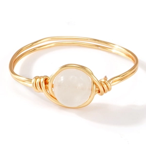 Handgemaakte gouden ring van gewikkeld draad met een doorschijnende witte edelsteen op wit
