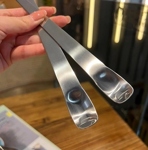 Detail view of two long-handled stainless steel dessert and filling spoons on wood