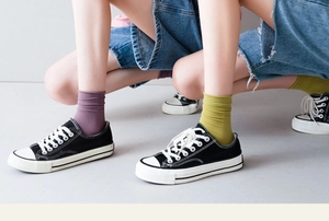 Detail of purple and lime green cotton knit crew socks styled with canvas sneakers