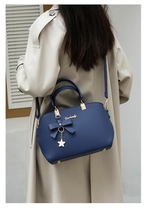 Detail of navy blue crossbody bag with lychee texture and star charm on trench coat