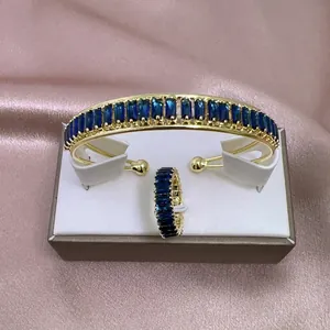 Detalle de un conjunto de pulsera y anillo chapados en oro con cristales azules rectangulares