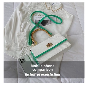 Detailed shot of white crocodile texture bag with green trim and bamboo top handle