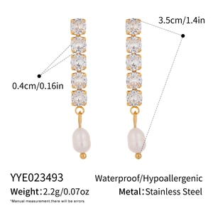 Détail macro de boucles d'oreilles dorées 18K avec zircone et perles en goutte d'eau