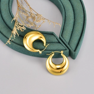 Vue détaillée de boucles d'oreilles créoles dorées polies sur velours vert