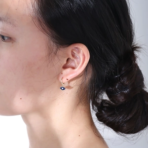 Close-up of golden evil eye drop earrings with blue enamel on a female model