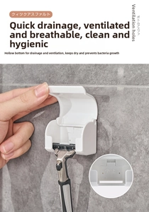 Close-up of a wall-mounted white razor holder with drainage hooks on a gray tiled wall