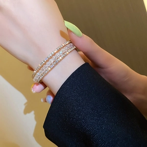 Detail of layered gold bracelet with white crystal beads and rhinestones on a wrist
