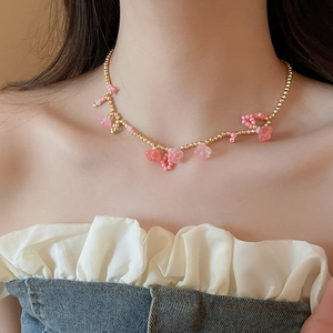 Gros plan sur les perles de fleurs roses et le collier de perles dorées d'un modèle