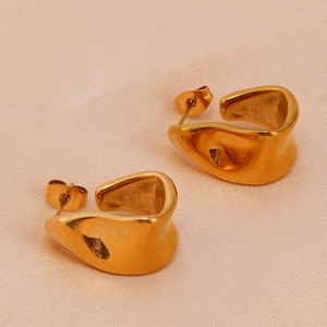 Detailed close-up of gold irregular wavy earrings on soft pink fabric texture