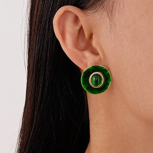 Boucles d'oreilles vintage rondes en émail vert émeraude et dorure sur un mannequin