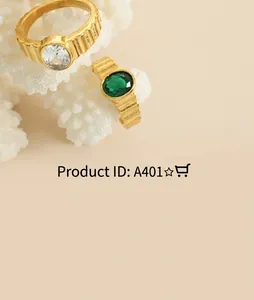 Close-up of gold rings with green and clear gemstones on white decorative coral