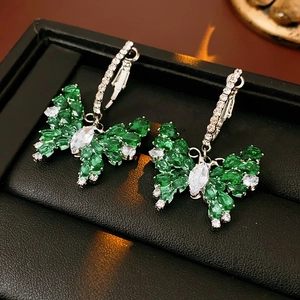 Close-up of green butterfly drop earrings with emerald zircons on black jewelry box