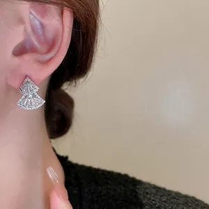 Silver-toned fan-shaped earrings with zircon pavé worn by a model in a luxury close-up