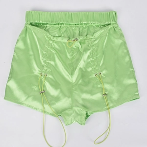 Detail of neon green satin shorts featuring an elastic waist and metallic drawstring toggles