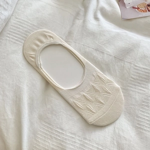 Close-up of beige mesh low-cut invisible socks with hollow-out knit patterns on bedsheet