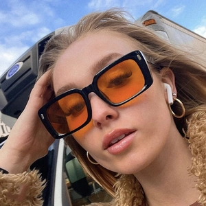 Vintage black square sunglasses with orange lenses shown on model in street style