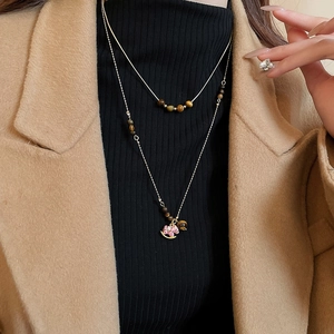 Gros plan d'un collier double en or avec perles d'oeil de tigre et pendentif cheval