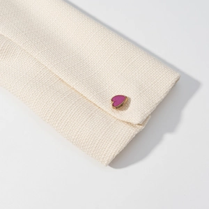 Dettaglio ravvicinato in tweed bianco sporco con bottone a forma di cuore dorato