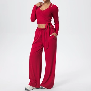 Détail de l'ensemble de yoga rouge avec haut court cache-cœur et pantalon large fluide