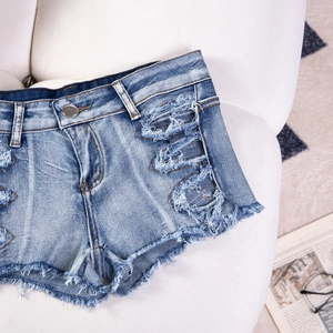 Dettaglio di pantaloncini di denim blu con orli sfrangiati su un divano bianco