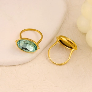 Macro shot of oval-cut green sapphire rings with vintage gold bands on marble