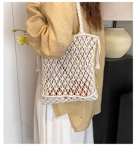 Close-up of beige handmade woven shoulder bag with cotton fringe and mesh hollow detail