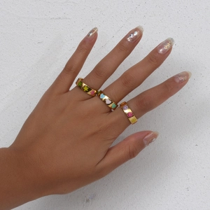 Detailed shot of gold plated rings featuring colorful enamel stars and smiley faces