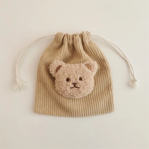 Macro detail of corduroy texture and plush bear ornament on drawstring storage pouch