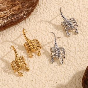 Detailed close-up of scorpion-shaped stud earrings in polished gold and silver finishes