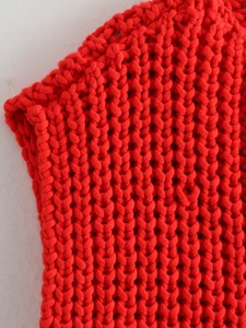 Macro view of bright red chunky knit vest showing detailed stitching and texture