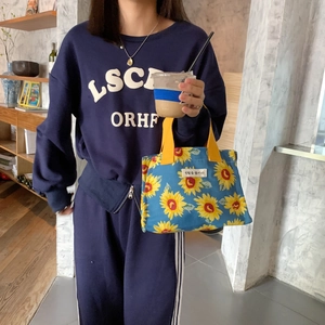 Detail of sunflower printed lunch bag with vibrant yellow straps and woven patch