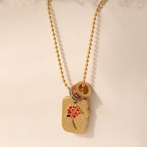 French vintage gold beaded necklace with colorful floral enamel square pendant on a wall