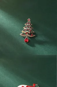 Close-up of a 4.5cm Christmas tree brooch with green enamel and red crystal drop pendant