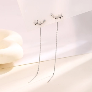 Detail of silver star tassel earrings with zircon stars and long hanging metal chains