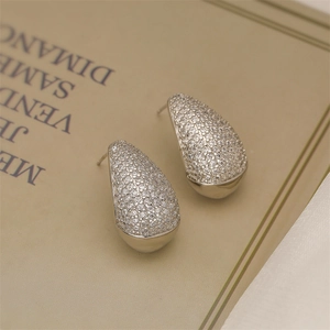Detailed view of silver teardrop earrings with pave zircons on vintage book pages