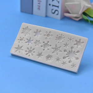 White silicone snowflake mold with various patterns on a blue background for DIY baking