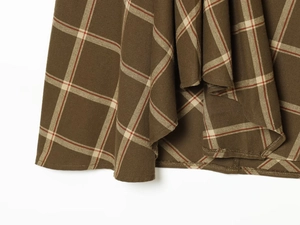 Detail shot of vintage plaid skirt hem with precise stitching on woven fabric