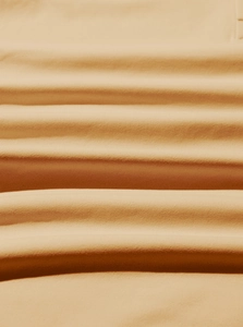 Macro shot of soft caramel jersey fabric texture showing high-density knit detail