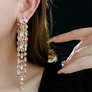 Macro view of long tassel drop earrings with pink and white rhinestones in gold setting