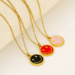 Close-up of colorful smiley face pendants in black, red, and pink on gold O-chains