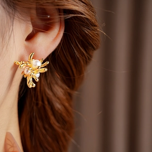 Detail von goldenen Blumenohrringen mit Perlen, getragen für einen eleganten Stil