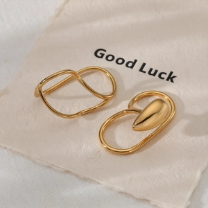 Minimalist gold irregular line ear cuffs and fluid drop earrings on fabric background