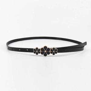 Detail of slim black leather belt featuring three floral buckles with golden accents