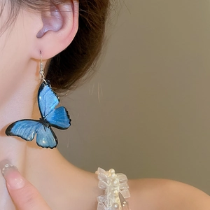 Close-up of a gradient blue butterfly earring worn on ear, showing sweet aesthetic detail