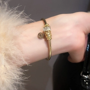 Détail d'un bracelet à breloques doré avec pendentif coeur et perles en zircone