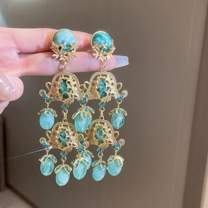 Detailed view of vintage gold hollow-out drop earrings with marble teal stones and crystals