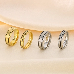 Dettaglio di anelli di coppia oro e argento con scanalature nere su fondo satinato