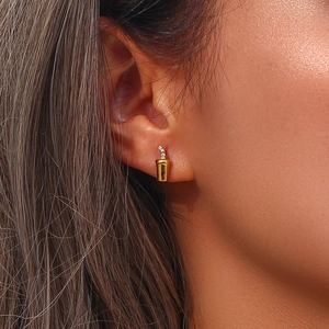 Close-up of gold coffee cup stud earring with zircon accents worn by a model
