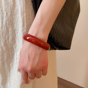 Detail of a minimalist dark red resin geometric round bangle on a woman's wrist