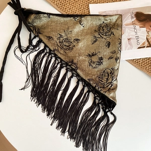 Detail of vintage gold shawl with black rose floral print and long fringe decorative trim